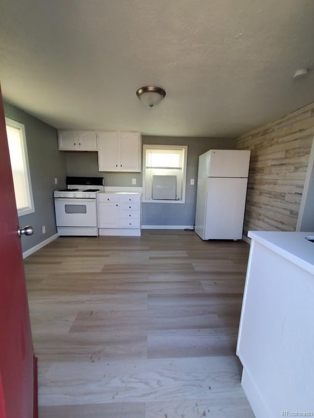 kitchen featuring light countertops, light wood-style flooring, white cabinets, white appliances, and baseboards