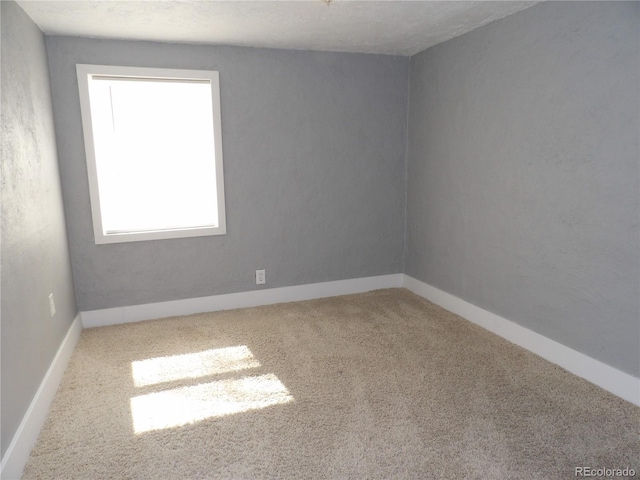 spare room featuring carpet flooring and baseboards