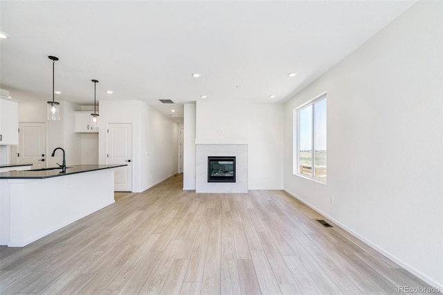 9360 Bahama Ct, Commerce City, CO 80022 - unfurnished living room with light wood-style floors, a glass covered fireplace, and recessed lighting