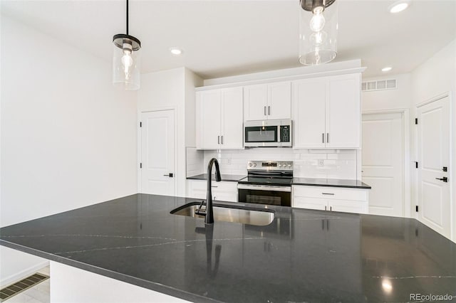 9360 Bahama Ct, Commerce City, CO 80022 - kitchen with appliances with stainless steel finishes, tasteful backsplash, recessed lighting, white cabinets, and hanging light fixtures