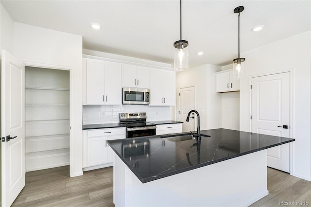 9360 Bahama Ct, Commerce City, CO 80022 - kitchen featuring appliances with stainless steel finishes, dark countertops, light wood-style floors, white cabinets, and pendant lighting
