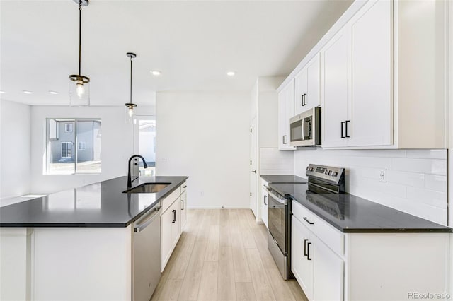 9360 Bahama Ct, Commerce City, CO 80022 - kitchen featuring stainless steel appliances, tasteful backsplash, light wood-style floors, white cabinetry, and a kitchen island with sink