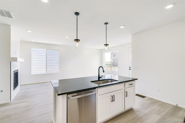 9360 Bahama Ct, Commerce City, CO 80022 - kitchen featuring stainless steel dishwasher, dark countertops, light wood finished floors, hanging light fixtures, and white cabinetry