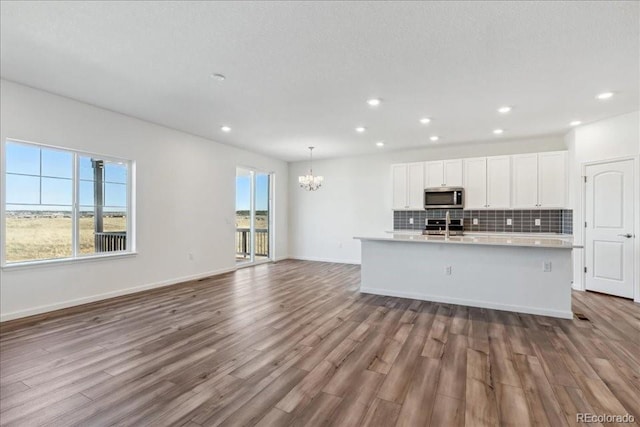 kitchen featuring light hardwood / wood-style floors, a center island with sink, an inviting chandelier, stainless steel appliances, and white cabinets