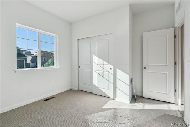 unfurnished bedroom with light colored carpet and a closet