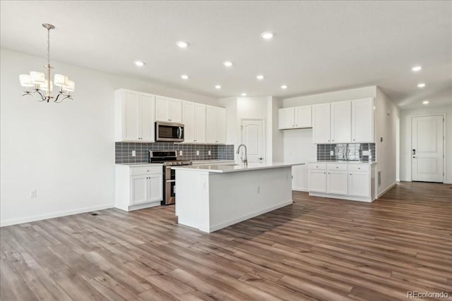 kitchen featuring white cabinetry, stainless steel appliances, and an island with sink