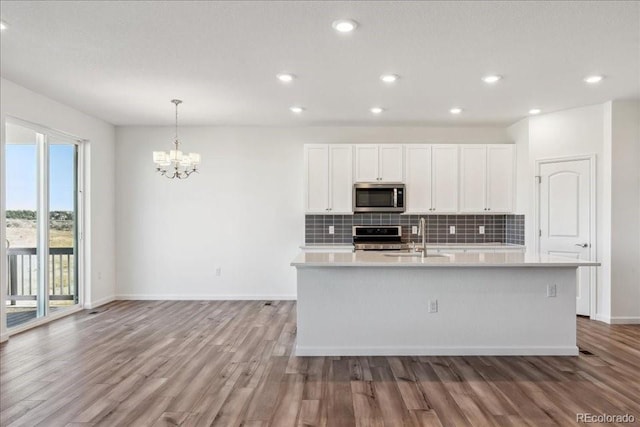 kitchen featuring appliances with stainless steel finishes, sink, white cabinetry, and a center island with sink