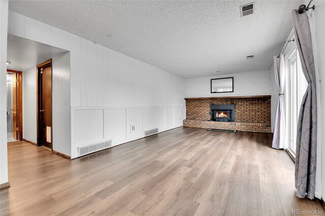 7796 S Marshall Ct, Littleton, CO 80128 - unfurnished living room with wood finished floors, healthy amount of natural light, a textured ceiling, and a decorative wall
