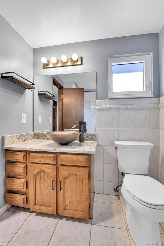 7796 S Marshall Ct, Littleton, CO 80128 - bathroom with toilet, vanity, tile patterned floors, and tile walls
