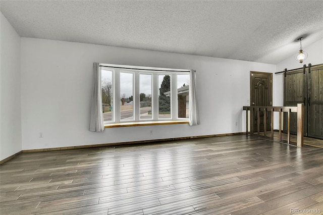7796 S Marshall Ct, Littleton, CO 80128 - unfurnished room featuring a barn door, a textured ceiling, wood finished floors, and lofted ceiling