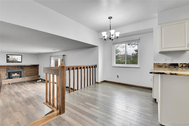 7796 S Marshall Ct, Littleton, CO 80128 - unfurnished dining area featuring a chandelier, a brick fireplace, and light wood-style flooring