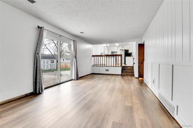 7796 S Marshall Ct, Littleton, CO 80128 - unfurnished living room with a textured ceiling and wood finished floors