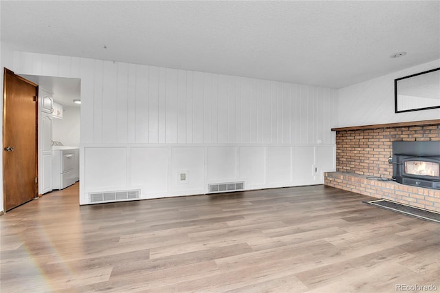 7796 S Marshall Ct, Littleton, CO 80128 - unfurnished living room featuring a decorative wall, washer and dryer, wood finished floors, and a textured ceiling