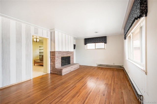 unfurnished living room with hardwood / wood-style floors, a fireplace, and a baseboard heating unit