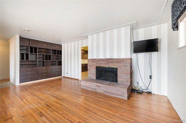 unfurnished living room featuring light hardwood / wood-style floors and a brick fireplace