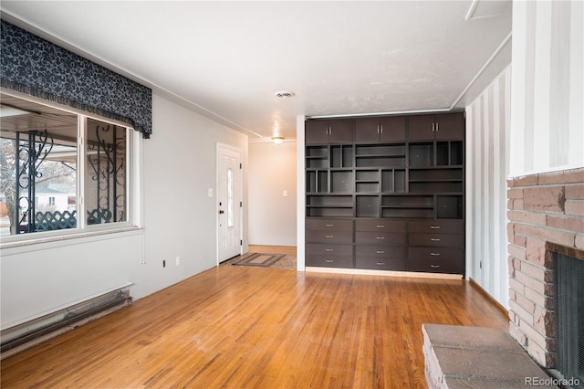 unfurnished living room with light hardwood / wood-style flooring and a brick fireplace