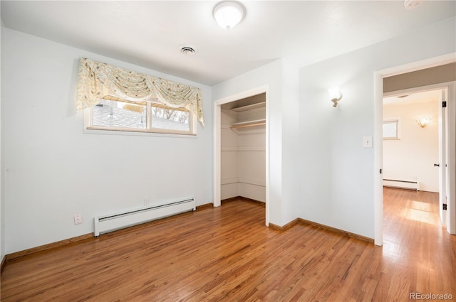 unfurnished bedroom with hardwood / wood-style floors, a closet, and a baseboard radiator