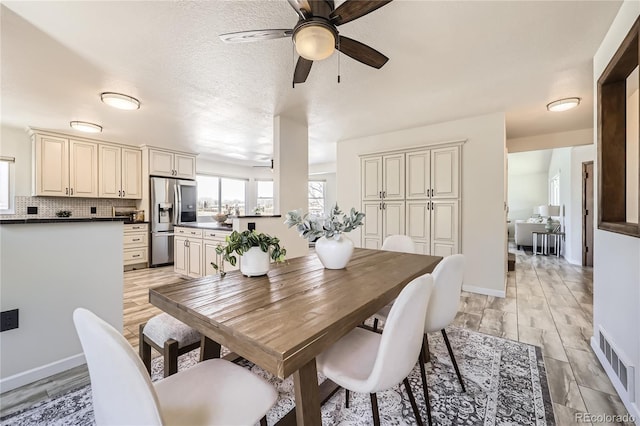 dining space featuring visible vents, ceiling fan, a textured ceiling, and baseboards