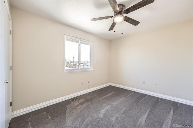 empty room with a ceiling fan, dark carpet, visible vents, and baseboards