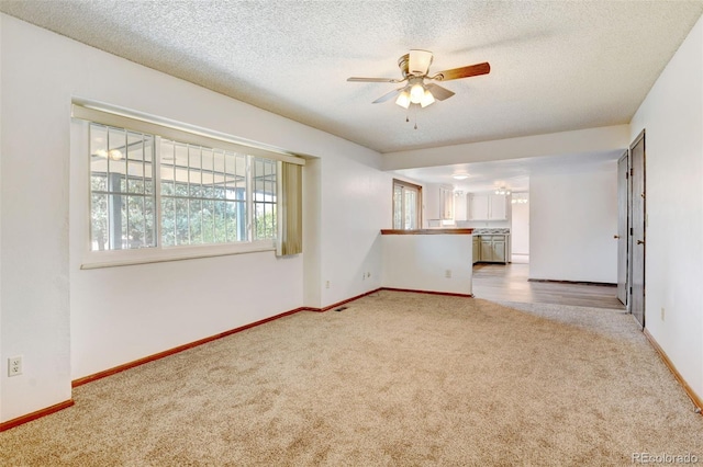 1487 S Zeno Way, Aurora, CO 80017 - unfurnished room with light carpet, a ceiling fan, baseboards, and a textured ceiling