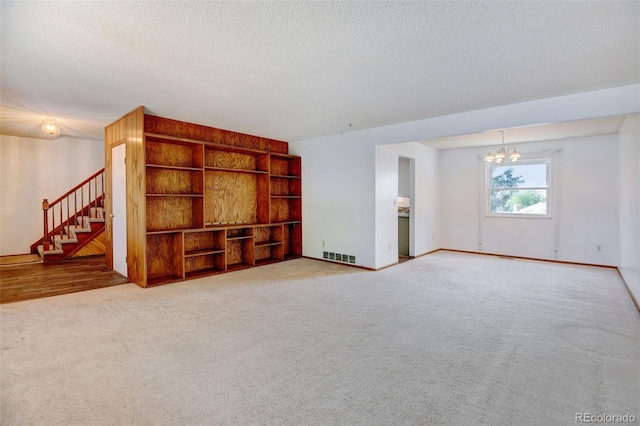 1487 S Zeno Way, Aurora, CO 80017 - carpeted spare room featuring a chandelier, stairs, a textured ceiling, baseboards, and built in features