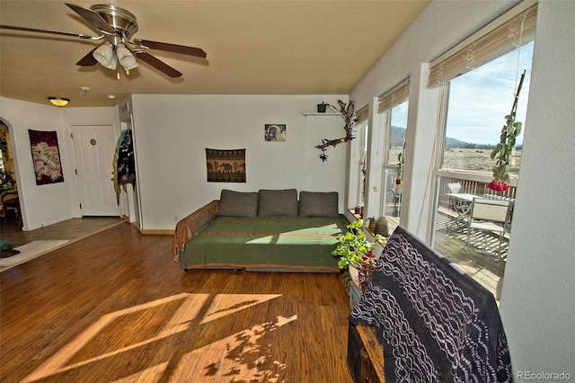 living room with ceiling fan, a textured ceiling, and dark hardwood / wood-style flooring