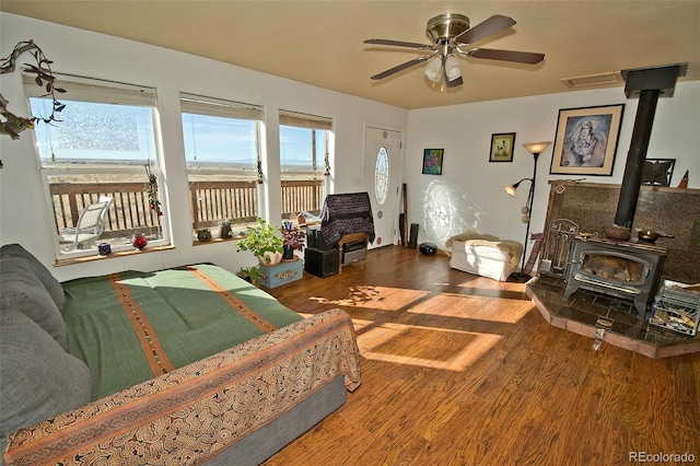 living room featuring ceiling fan, a wood stove, and hardwood / wood-style floors