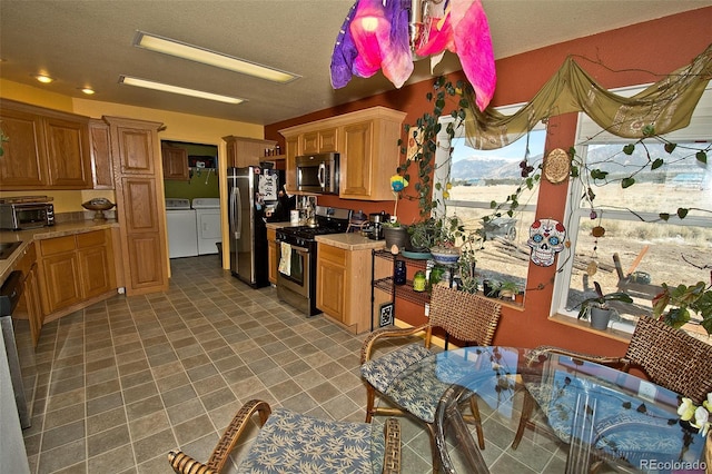 kitchen with a healthy amount of sunlight, washing machine and dryer, and appliances with stainless steel finishes