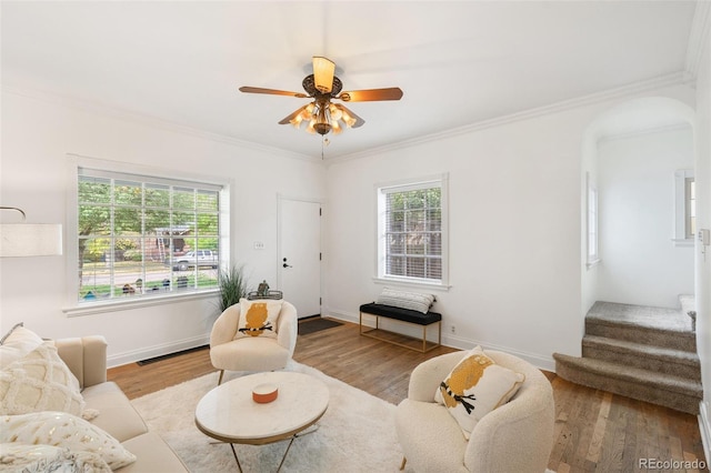 living room with light wood-type flooring, ornamental molding, and a wealth of natural light