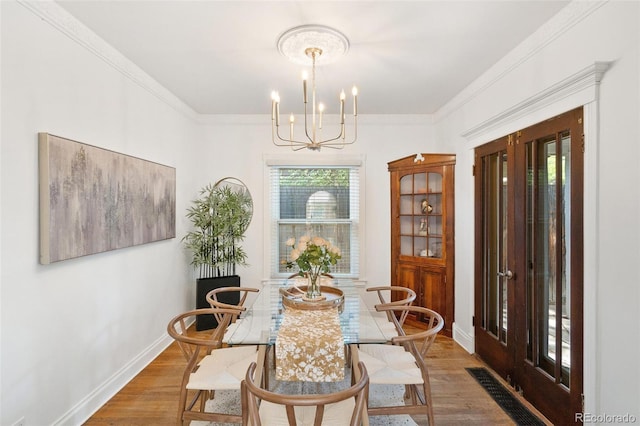 dining area with crown molding, a chandelier, and wood-type flooring