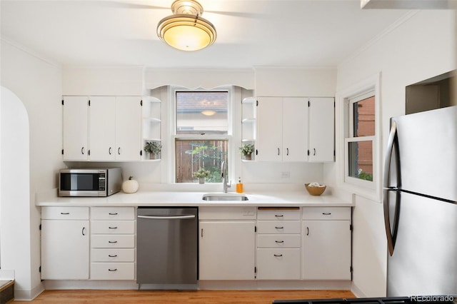 kitchen featuring appliances with stainless steel finishes, ornamental molding, sink, and white cabinetry