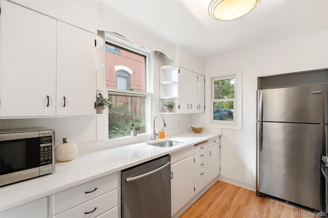 kitchen with white cabinetry, light hardwood / wood-style floors, appliances with stainless steel finishes, and sink