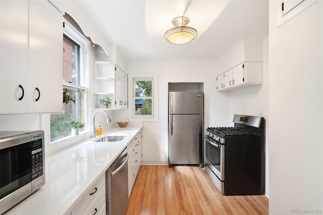 kitchen with light hardwood / wood-style floors, white cabinetry, stainless steel appliances, and sink