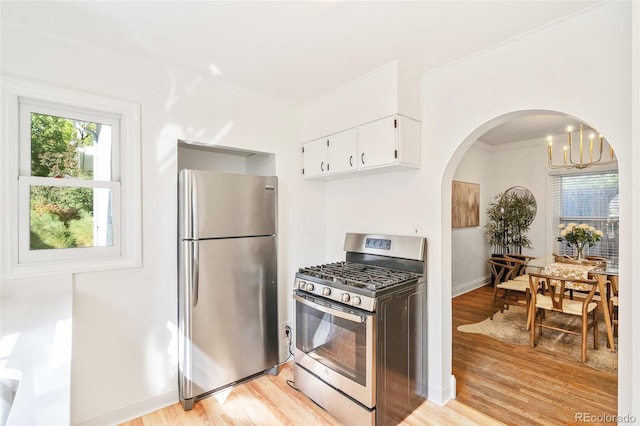 kitchen with appliances with stainless steel finishes, light hardwood / wood-style flooring, decorative light fixtures, white cabinets, and ornamental molding