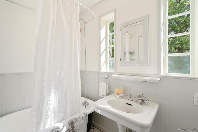 bathroom featuring a healthy amount of sunlight, shower / bathtub combination with curtain, and sink