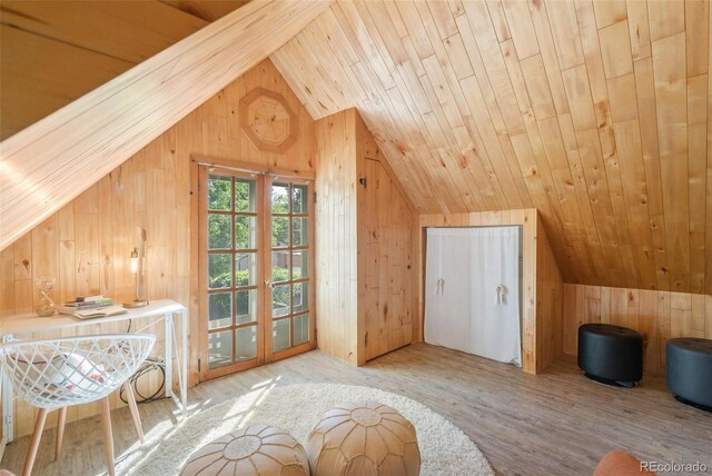 additional living space featuring light wood-type flooring, wooden ceiling, vaulted ceiling, and wooden walls