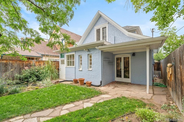 rear view of property with french doors, a patio, and a lawn