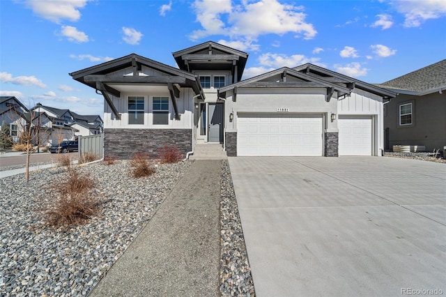 view of front of house featuring stone siding, board and batten siding, driveway, and a garage