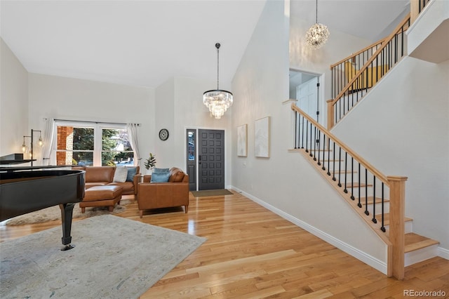 entryway featuring a towering ceiling, light hardwood / wood-style flooring, and a notable chandelier