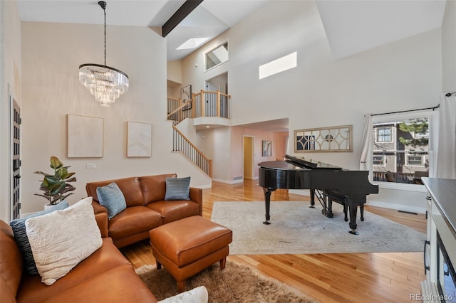 living room with light hardwood / wood-style flooring, a towering ceiling, and a notable chandelier