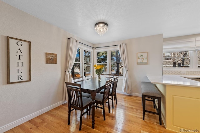 dining space with a chandelier, a textured ceiling, and light hardwood / wood-style flooring