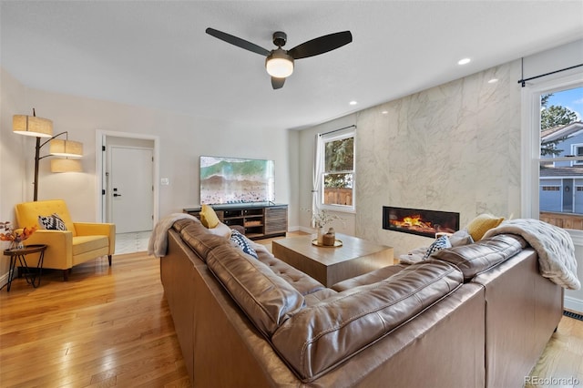 living room with ceiling fan, a healthy amount of sunlight, a fireplace, and light hardwood / wood-style flooring