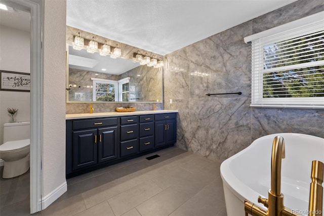 bathroom featuring vanity, tile patterned flooring, toilet, tile walls, and a tub