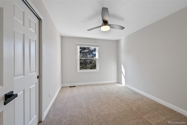 spare room featuring ceiling fan and light carpet