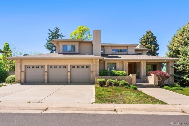 4800 E Cedar Ave, Denver, CO 80246 - prairie-style home featuring concrete driveway, stucco siding, an attached garage, covered porch, and brick siding