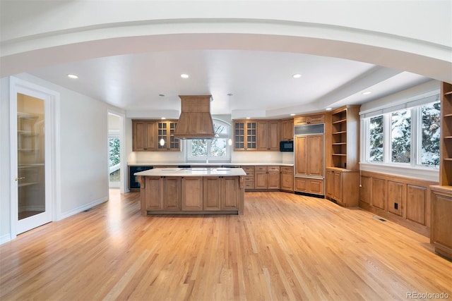 4800 E Cedar Ave, Denver, CO 80246 - kitchen featuring custom range hood, arched walkways, open shelves, light wood finished floors, and brown cabinets