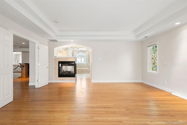 4800 E Cedar Ave, Denver, CO 80246 - unfurnished living room featuring a raised ceiling, light wood-type flooring, recessed lighting, a multi sided fireplace, and baseboards