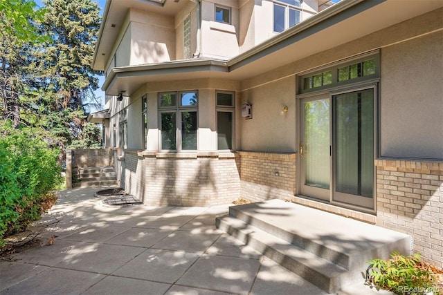 4800 E Cedar Ave, Denver, CO 80246 - view of exterior entry featuring brick siding, stucco siding, and a patio