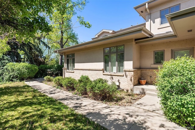 4800 E Cedar Ave, Denver, CO 80246 - view of property exterior featuring brick siding, stucco siding, and a lawn