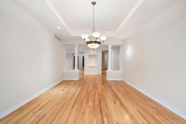 4800 E Cedar Ave, Denver, CO 80246 - empty room featuring ornate columns, a tray ceiling, light wood-style floors, baseboards, and a chandelier
